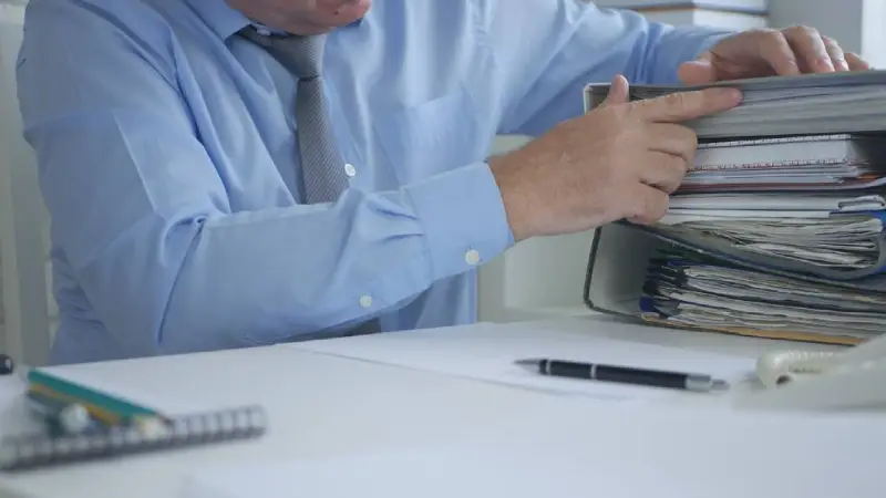 Facilities manager reviewing TM44 compliance paperwork at a desk in a commercial setting